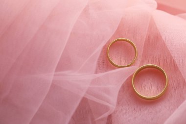 Pembe kumaşta güzel altın alyanslar, üst manzara. Metin için boşluk
