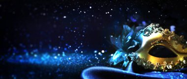 Siyah arka planda güzel bir karnaval maskesi, mavi ışık ve parıltı, bokeh etkisi. Metin için alanı olan pankart tasarımı