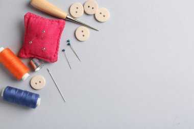 Açık gri arka planda farklı dikiş malzemeleri, düz zemin. Metin için boşluk