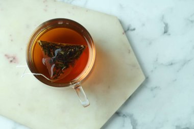 Cam bardakta çay poşeti, açık mermer masada sıcak içecek, üst manzara. Metin için boşluk