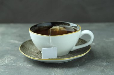 Gri dokulu masada sıcak içecekle birlikte çay poşeti.