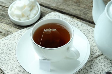 Çay poşeti sıcak içecek, çaydanlık ve şeker küpleri ahşap masada, yakın plan.