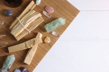 Palo Santo sopaları ve değerli taşlar beyaz ahşap masada, düz yerde. Metin için boşluk