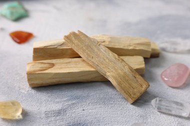 Palo santo sopaları ve açık gri desenli masa üzerindeki değerli taşlar, yakın plan.