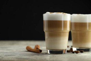 Bardakta latte macchiato, kahve çekirdekleri ve gri masada tarçın, yakın plan. Metin için boşluk