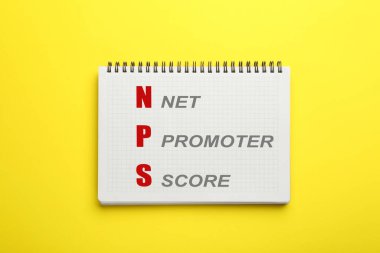 NPS (net promoter score) in notebook on yellow background, top view. Customer satisfaction assessment clipart