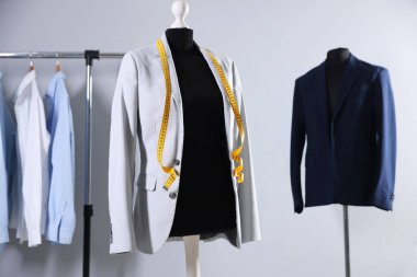 Ceketli kadın manken ve terzi dükkanında mezura.