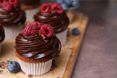 Kahverengi masada çikolatalı kremalı ve dutlu lezzetli kekler, yakın plan. Metin için boşluk