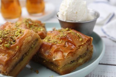 Beyaz ahşap masada ezilmiş fındıklı ve dondurmalı enfes baklava, yakın plan.