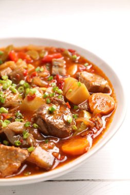 Lezzetli güveç, kasede sebzeler, beyaz ahşap masa, yakın plan.