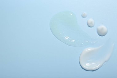 Açık mavi arka planda krema ve jel örnekleri, üst manzara. Metin için boşluk