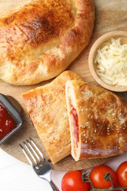 Beyaz ahşap masada servis edilen taze calzone pizza parçaları.