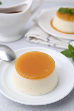 Beyaz masada servis edilen karamel soslu lezzetli puding, yakın plan.