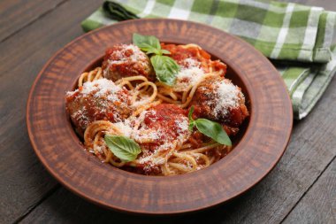 Köfteli, peynirli ve fesleğenli lezzetli makarna ahşap masada, yakın plan.