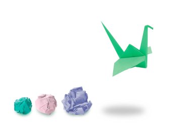 Yeşil origami vinç ve beyaz arka planda buruşmuş kağıt toplar. Dönüşüm veya yeni fikirler kavramı
