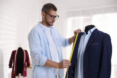 Atölyede bant ile siyah ceketi ölçen adam