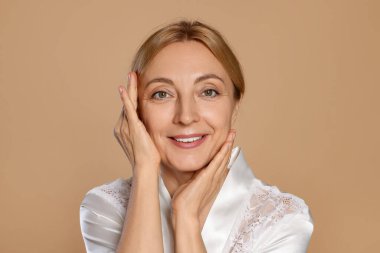Bej arka planda sağlıklı ciltli gülümseyen kadın portresi