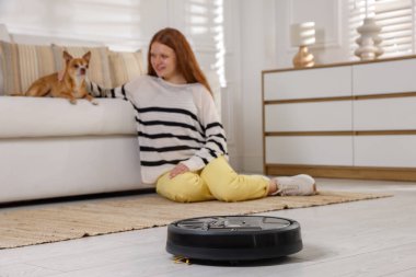 Genç kız ve onun sevimli Chihuahua köpeği evde, robotik elektrik süpürgesine odaklan.
