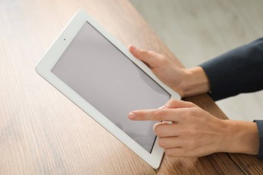 İş kadını, kapalı bir masada tablet kullanıyor, yakın plan. Modern teknoloji