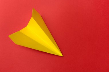 Kırmızı arka planda el yapımı sarı kağıt uçak, üst manzara. Metin için boşluk