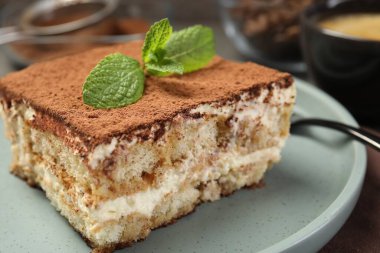 Bir parça lezzetli tiramisu. Masada taze nane var. Yakın plan.