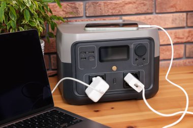 İçerideki ahşap masada taşınabilir elektrik santralinden şarj edilen cihazlar