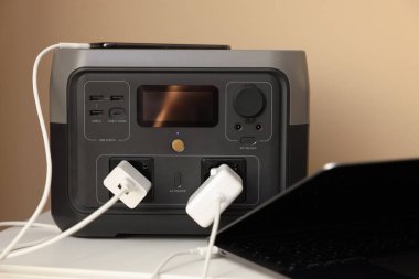 İçerideki komodinin üzerinde taşınabilir elektrik santralinden şarj olan aygıtlar