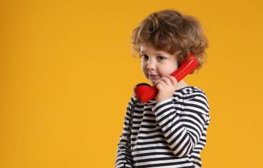 Telefon ahizesi turuncu arka planda, mesaj için yeri olan sevimli küçük bir çocuk.