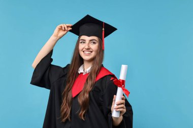 Mezuniyetten sonra açık mavi arka planda diplomalı mutlu bir öğrenci.