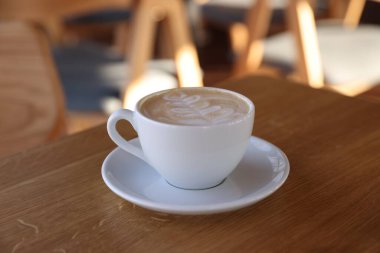 Kafedeki ahşap masada bir fincan aromatik kahve, yakın plan.