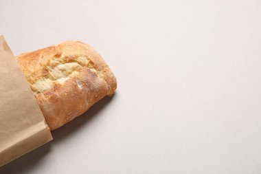 Açık gri masa üzerinde taze baget ve kağıt torba, üst manzara. Metin için boşluk