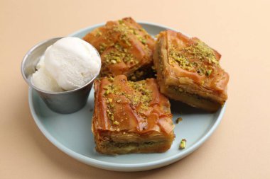 Bej masanın üzerinde ezilmiş fındıklı ve dondurmalı enfes baklava, yakın plan.