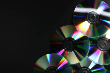 Siyah arkaplanda parlak CD 'ler, üst görünümde. Metin için boşluk