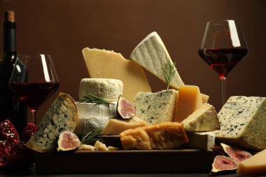 Different types of cheese, rosemary, figs, pomegranate and wine on table clipart