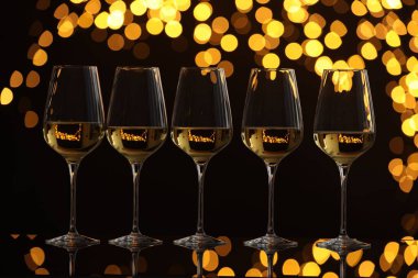 Ayna yüzeyinde gözlüklü lezzetli beyaz şarap bulanık ışıklı karanlık arka plana karşı. Bokeh etkisi