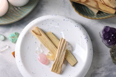 Palo santo sopaları ve açık gri desenli masa üzerinde değerli taşlar düz yatıyordu.