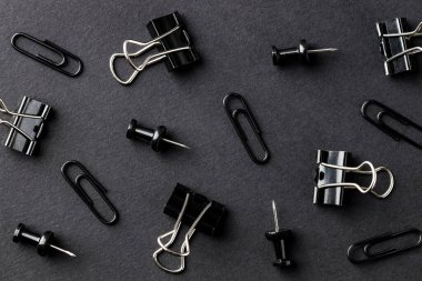 Paper clips and pins on black background, flat lay