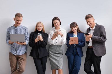 Beyaz duvarın yanında farklı aletler kullanan bir grup insan. Modern teknoloji
