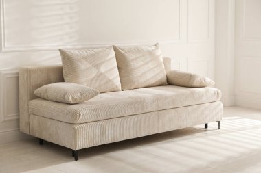 Işık odasında yastıkları olan rahat bir kanepe.