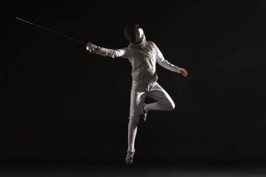 Fencer with epee practicing on black background clipart