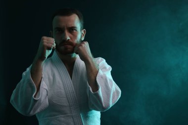 Üniformalı bir adam renkli ışıklarla ve dumanla karate yapıyor. Metin için boşluk