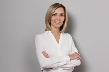 Gri arka planda beyaz gömlekli iş kadını portresi