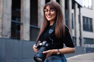 Binanın yakınında dijital kamerası olan profesyonel bir fotoğrafçı.