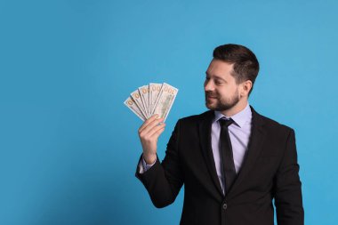 Açık mavi arkaplanda dolar banknotları olan bankacı, metin için boşluk