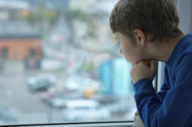 Autism concept. Lonely little boy near window at home, space for text clipart