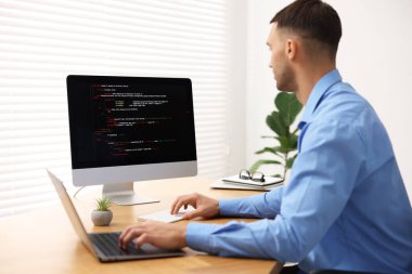 Bilgisayar ve dizüstü bilgisayarla çalışan bir programcı.