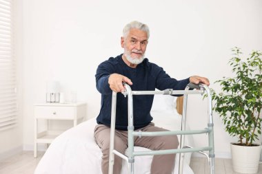 Hastane koğuşunda yatakta yürüyen yaşlı bir adam.