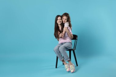 Açık mavi arkaplanda güzel kız kardeşlerin portresi