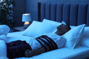 Uyurgezer bir adam yatakta çığlık atıyor.