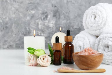 Beyaz masa üzerinde kozmetik ürünleri ve havlularla spa kompozisyonu